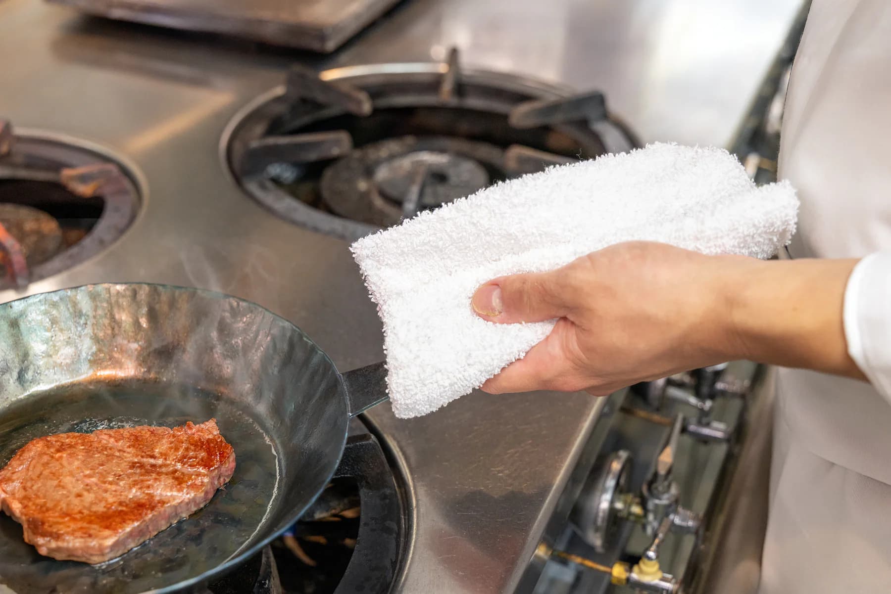 布巾を介して鉄製の取っ手を持つ手元